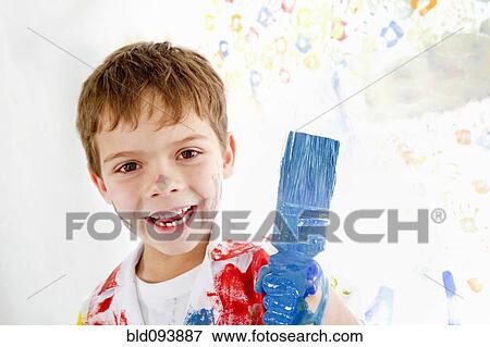 Stock Photo - Messy Hispanic boy holding paintbrush. Fotosearch