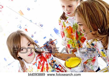 Stock Photo - Messy Hispanic mother painting daughter's face. Fotosearch