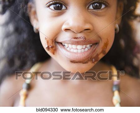 Stock Image - Mixed race girl with chocolate on her face. Fotosearch