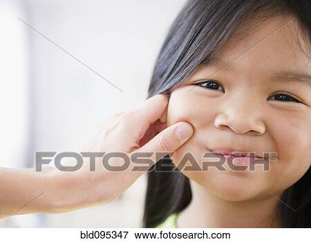 Stock Photo - Mother pinching Korean girl's cheek. Fotosearch