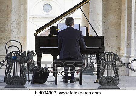 Stock Image - Pianist playing piano outdoors. Fotosearch