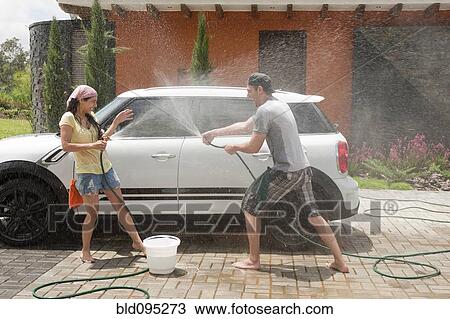 Stock Image - Playful Hispanic couple washing car together. Fotosearch