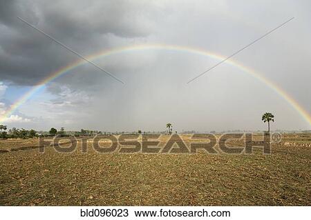 Stock Image - Rainbow over field. Fotosearch