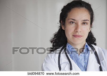 Stock Image - Serious Hispanic doctor in lab coat. Fotosearch