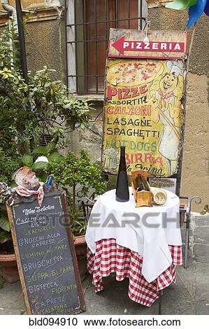 Stock Image - Sign and table outside pizzeria. Fotosearch