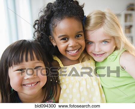 Stock Image - Smiling girls hugging each other. Fotosearch