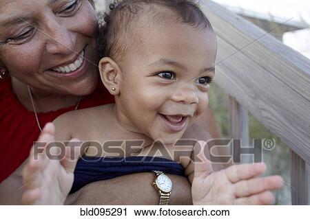 Smiling grandmother holding granddaughter outdoors View Large Photo Image Stock Image - Smiling grandmother holding granddaughter outdoors. Fotosearch