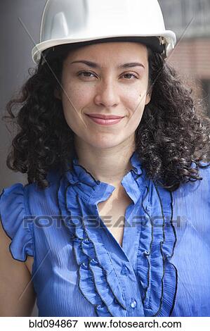 Stock Photo - Smiling Hispanic businesswoman wearing hard-hat. Fotosearch