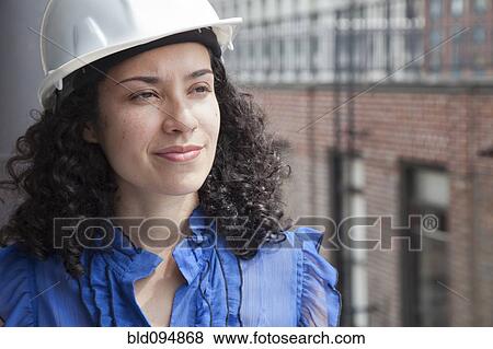 Stock Photo - Smiling Hispanic businesswoman wearing hard-hat. Fotosearch