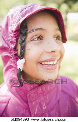 Stock Image - Smiling Hispanic girl in rain coat. Fotosearch