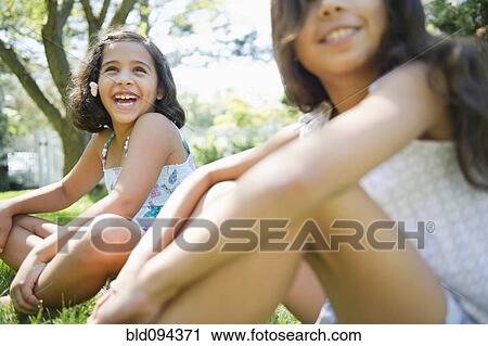 Smiling Hispanic girls sitting in grass together View Large Photo Image Stock Image - Smiling Hispanic girls sitting in grass together. Fotosearch