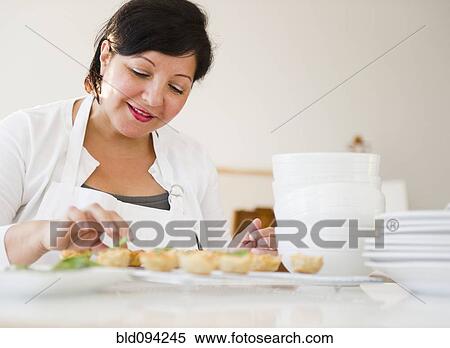 Stock Photography - Smiling Hispanic woman baking. Fotosearch