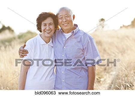 Smiling senior Chinese couple standing in field View Large Photo Image Stock Image - Smiling senior Chinese couple standing in field. Fotosearch