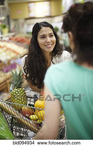 Picture - Women talking in grocery store. Fotosearch