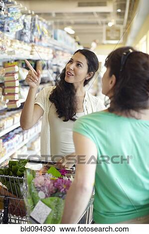 Stock Image - Women talking together in grocery store. Fotosearch