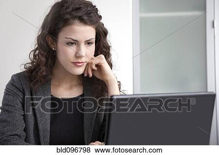 Stock Photo - Businesswoman using laptop at desk. Fotosearch