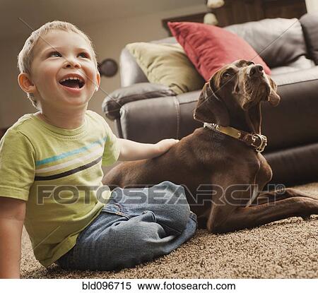 Stock Photography - Caucasian boy sitting on floor with dog. Fotosearch