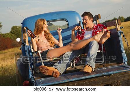 Stock Photo - Caucasian couple drinking beer in back of truck. Fotosearch