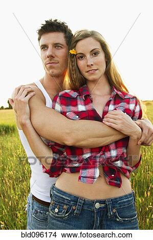 Picture - Caucasian couple hugging in field. Fotosearch