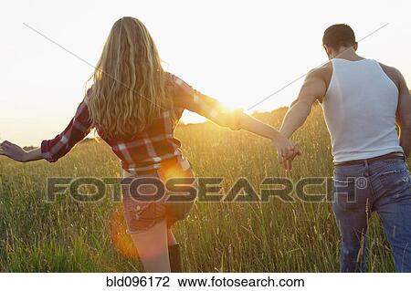 Caucasian couple walking in field holding hands View Large Photo Image Stock Image - Caucasian couple walking in field holding hands. Fotosearch