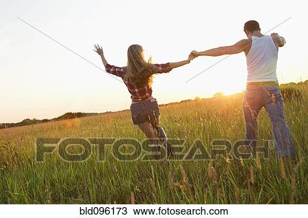 Caucasian couple walking in field holding hands View Large Photo Image Stock Image - Caucasian couple walking in field holding hands. Fotosearch