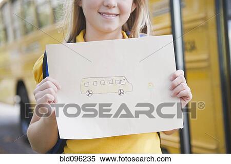 Stock Photography - Caucasian girl holding drawing of school bus. Fotosearch