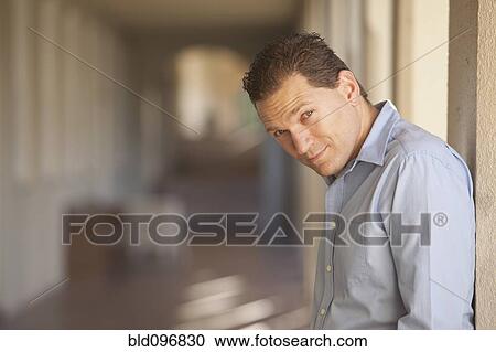 Stock Image - Caucasian man leaning on pillar. Fotosearch