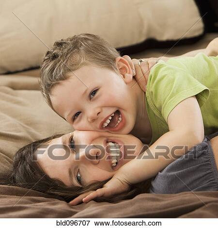 Stock Photo - Caucasian mother and son laying on bed. Fotosearch