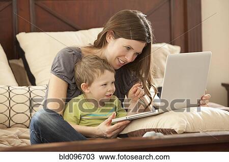 Caucasian mother and son using laptop on bed View Large Photo Image Stock Image - Caucasian mother and son using laptop on bed. Fotosearch