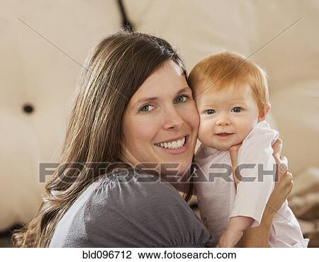 Stock Image - Caucasian mother holding baby daughter. Fotosearch