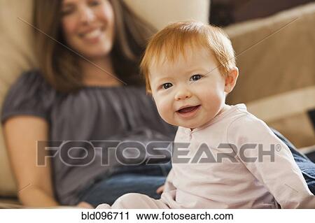Caucasian mother sitting on bed with baby daughter View Large Photo Image Stock Image - Caucasian mother sitting on bed with baby daughter. Fotosearch