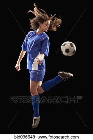 Stock Photo - Caucasian soccer player kicking ball. Fotosearch
