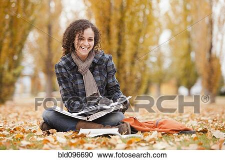 Stock Image - Caucasian woman doing home work in autumn leaves. Fotosearch
