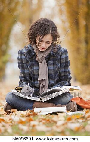 Stock Image - Caucasian woman doing home work in autumn leaves. Fotosearch