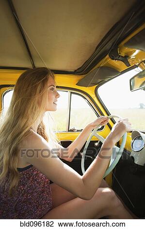 Stock Image - Caucasian woman driving old-fashioned car. Fotosearch