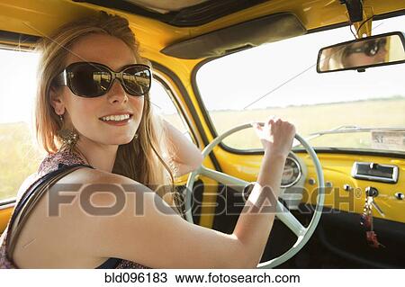 Stock Image - Caucasian woman driving old-fashioned car. Fotosearch