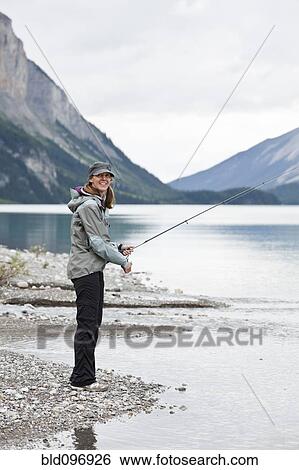 Stock Photograph - Caucasian woman fishing in Maligne Lake. Fotosearch