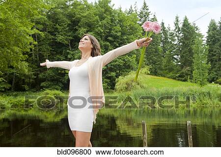 Caucasian woman holding flowers near pond View Large Photo Image Stock Image - Caucasian woman holding flowers near pond. Fotosearch