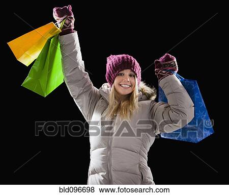 Stock Photo - Caucasian woman in coat holding shopping bags. Fotosearch