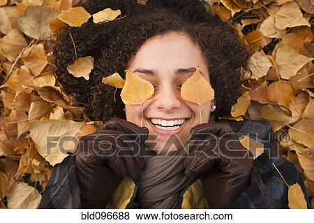 Stock Photo - Caucasian woman laying in autumn leaves. Fotosearch