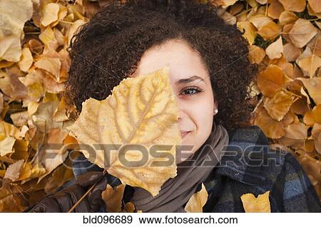 Stock Photo - Caucasian woman laying in autumn leaves. Fotosearch
