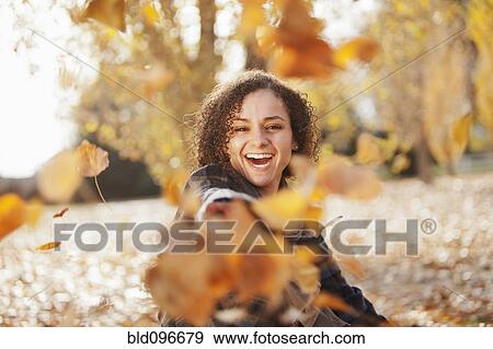 Stock Photo - Caucasian woman playing in autumn leaves. Fotosearch