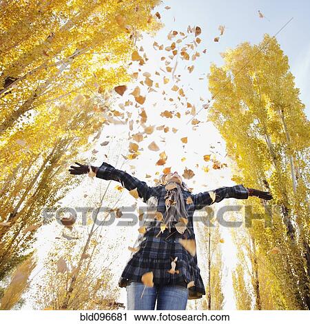 Stock Image - Caucasian woman playing with autumn leaves. Fotosearch