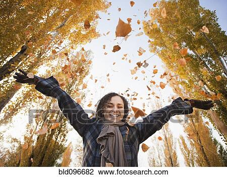 Stock Image - Caucasian woman playing with autumn leaves. Fotosearch