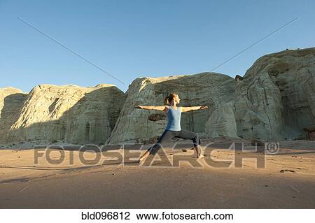Stock Image - Caucasian woman practicing yoga in desert. Fotosearch