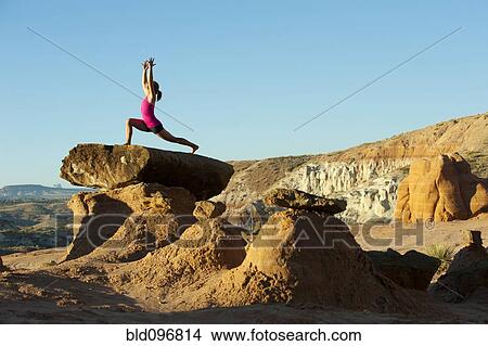 Picture - Caucasian woman practicing yoga on top of rock formation. Fotosearch