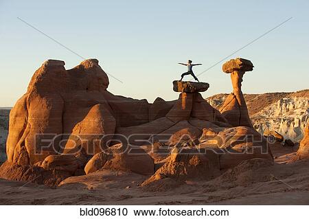 Stock Image - Caucasian woman practicing yoga on top of rock formation. Fotosearch