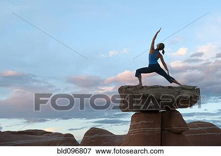 Stock Photo - Caucasian woman practicing yoga on top of rock formation. Fotosearch