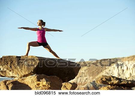 Stock Photography - Caucasian woman practicing yoga on top of rock formation. Fotosearch