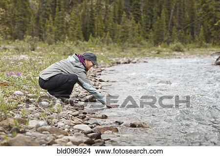 Caucasian woman reaching into stream View Large Photo Image Picture - Caucasian woman reaching into stream. Fotosearch